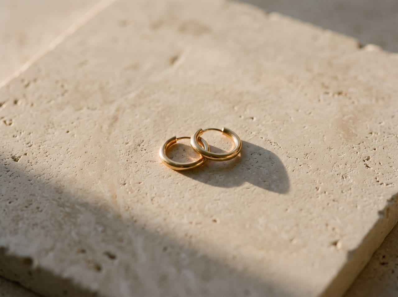 Gold earrings on a stone surface